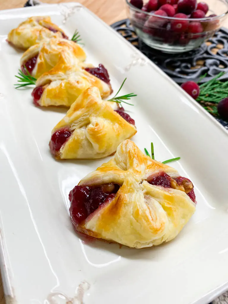 cranberry brie bites plated with cranberries, rosemary