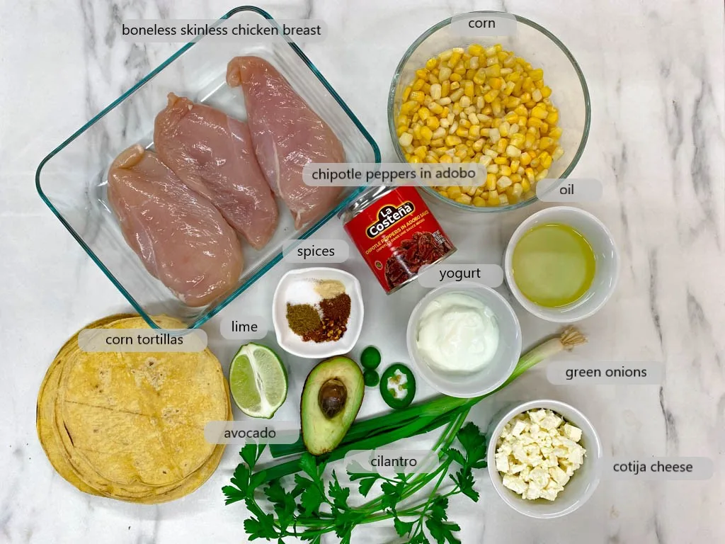 bowls with ingredients for street corn tacos, chicken, corn, oil, yourt, green onions, cotija cheese, cilantro, avocado, lime, spices, corn tortillas