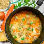 a pot of turkey meatball orzo soup with bread, carrots, onion, garlic, parsley and parmesan cheese around the bowls