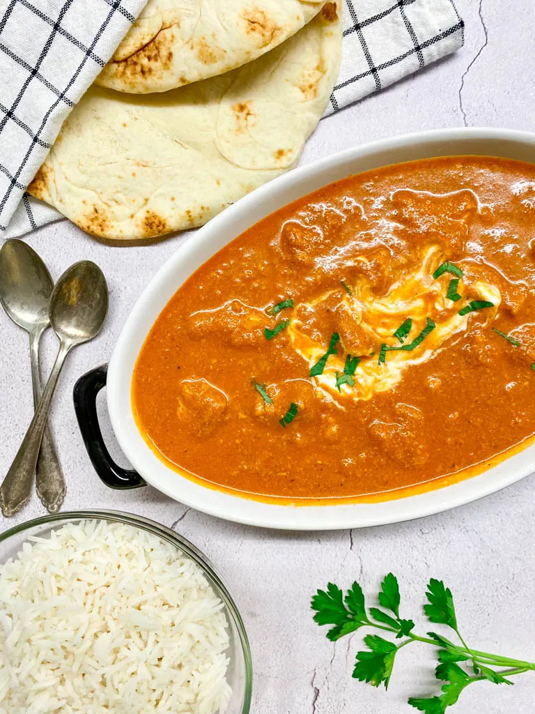 bowl of butter chicken with rice and naan bread