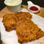 corn flake crusted fish on a wood board