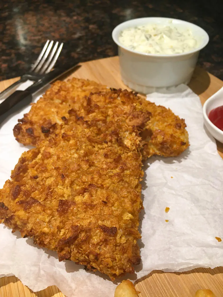 corn flake crusted fish on a wood board