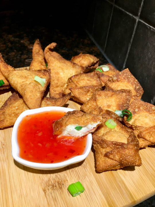 Crab Rangoons and Thai Chili Dip on a wood cutting board