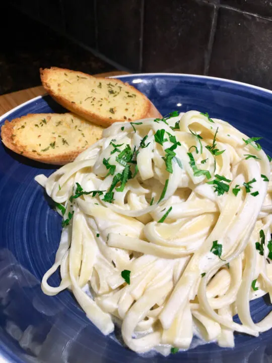 Fettucine Alfredo with garlic bread in a blue bowl