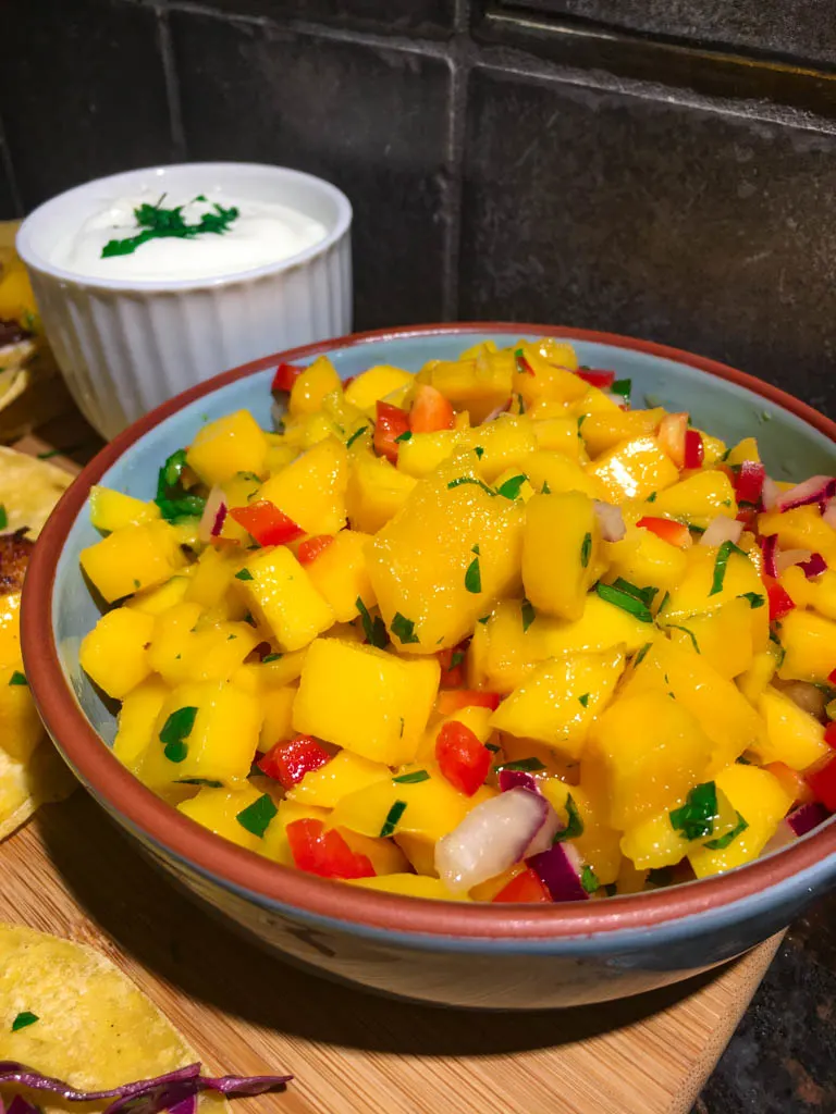 mango salsa plated in a blue bowl on a wood board