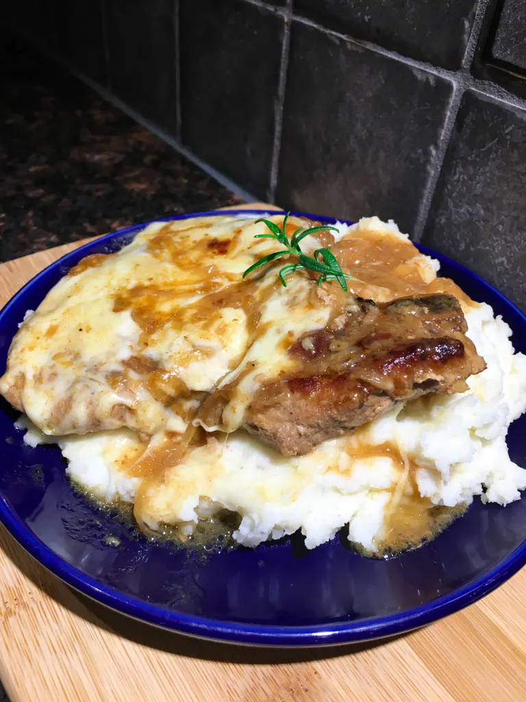 French Onion Pork Chops on a blue plate with mashed potatoes