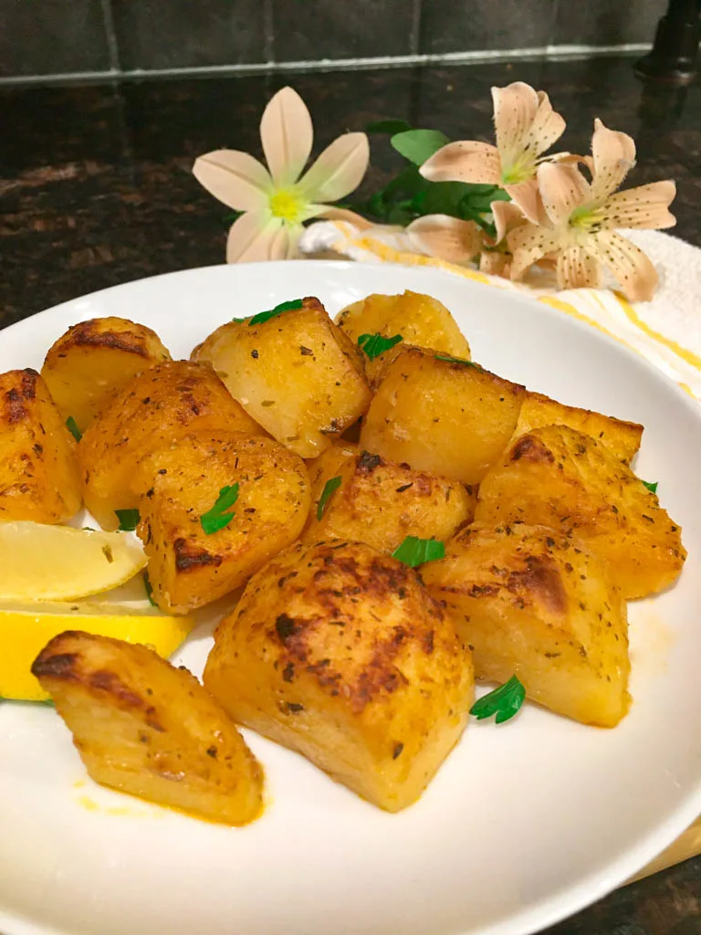 greek roasted potatoes on a white plate with lemon