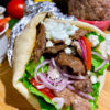 greek gyro pita plated with tomatoes, onion and tzatziki