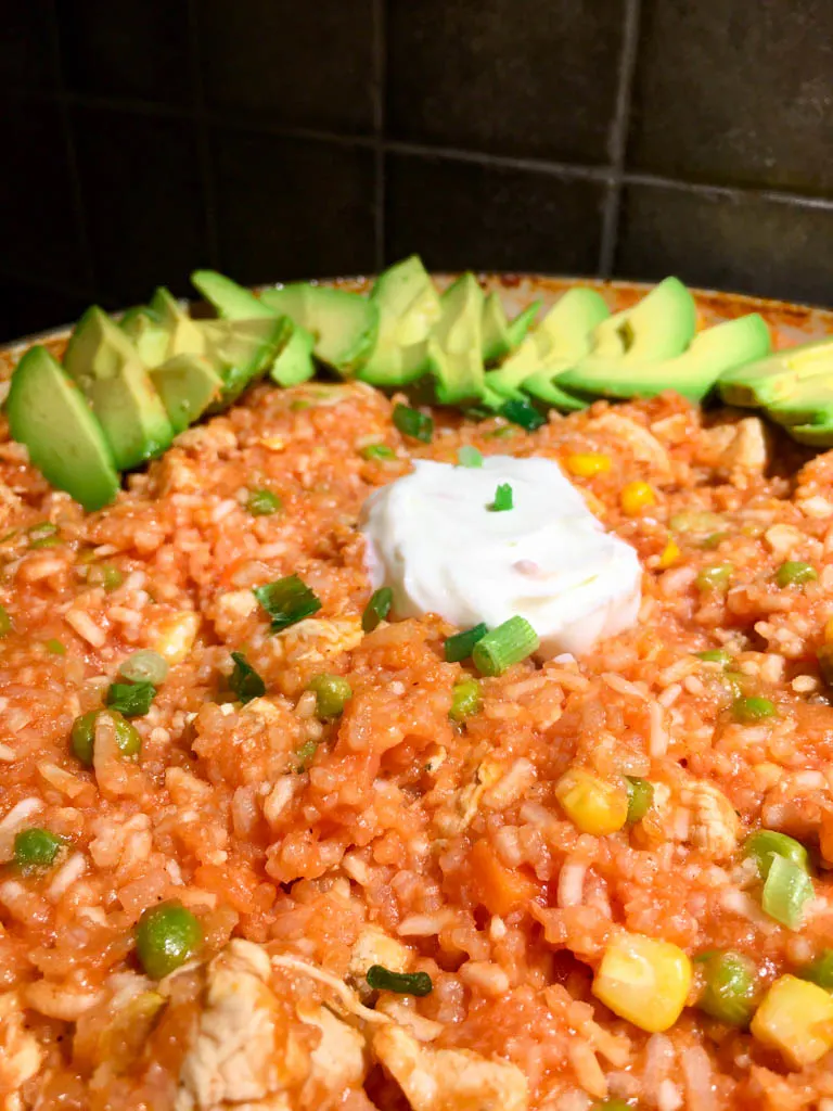 One Pan Chicken and Rice plated with avocado and sour cream