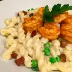 Pancetta and Peas Alfredo Pasta on a white plate with shrimp