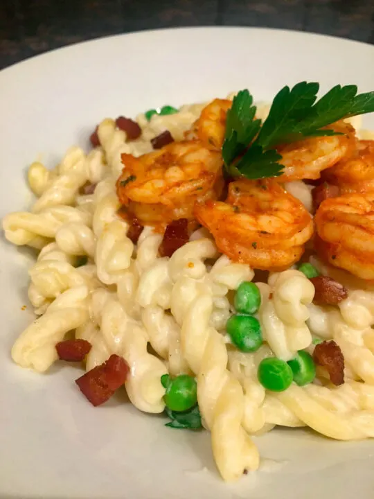 Pancetta and Peas Alfredo Pasta on a white plate with shrimp