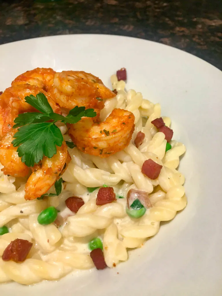 Pancetta and Peas Alfredo Pasta on a white plate with shrimp