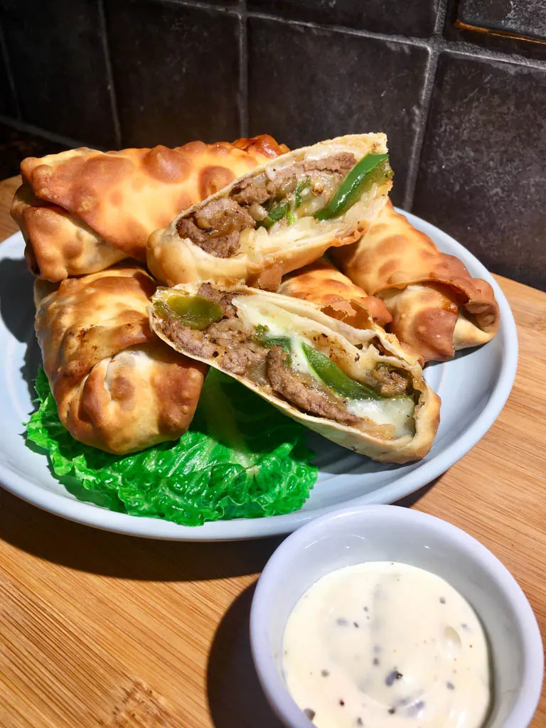 philly cheesesteak egg rolls on a blue plate