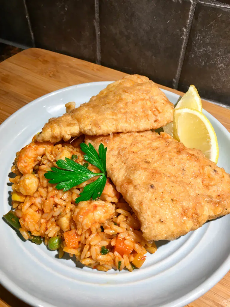 Portuguese Fried Fish Fillets on a blue plate with seafood rice