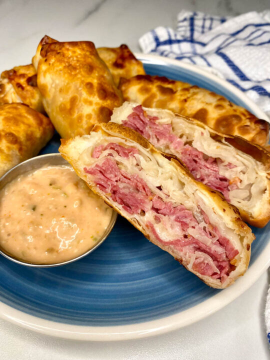 reuben egg rolls on a blue plate with thousand island dipping sauce