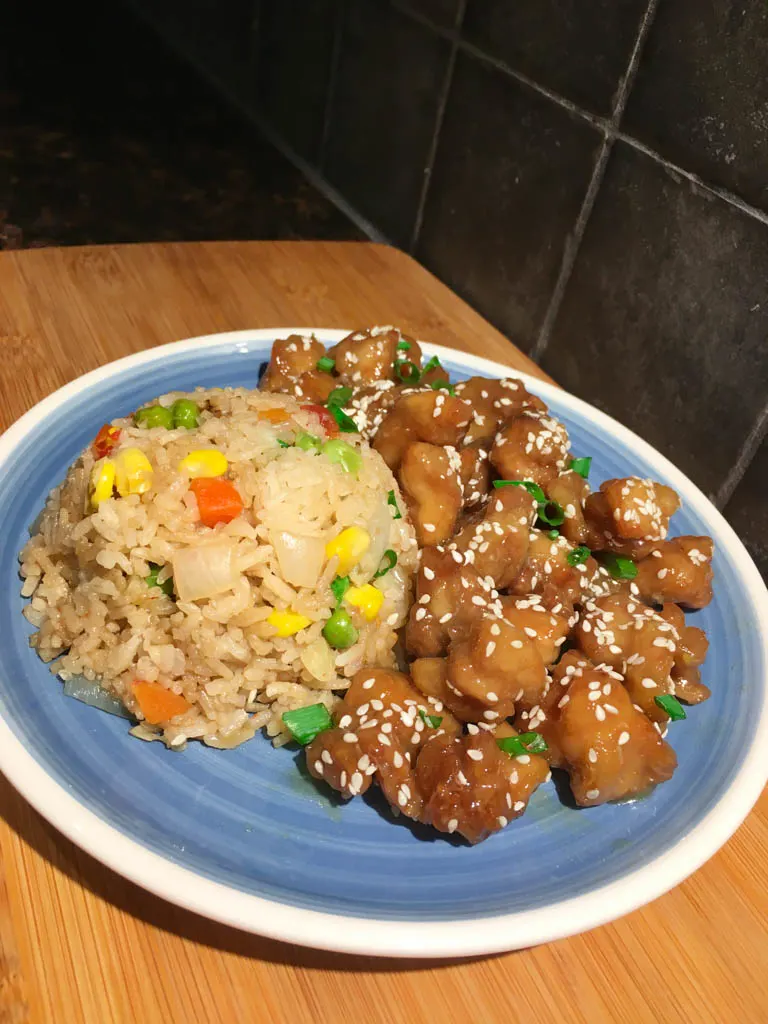 sesame chicken and fried rice on a blue plate