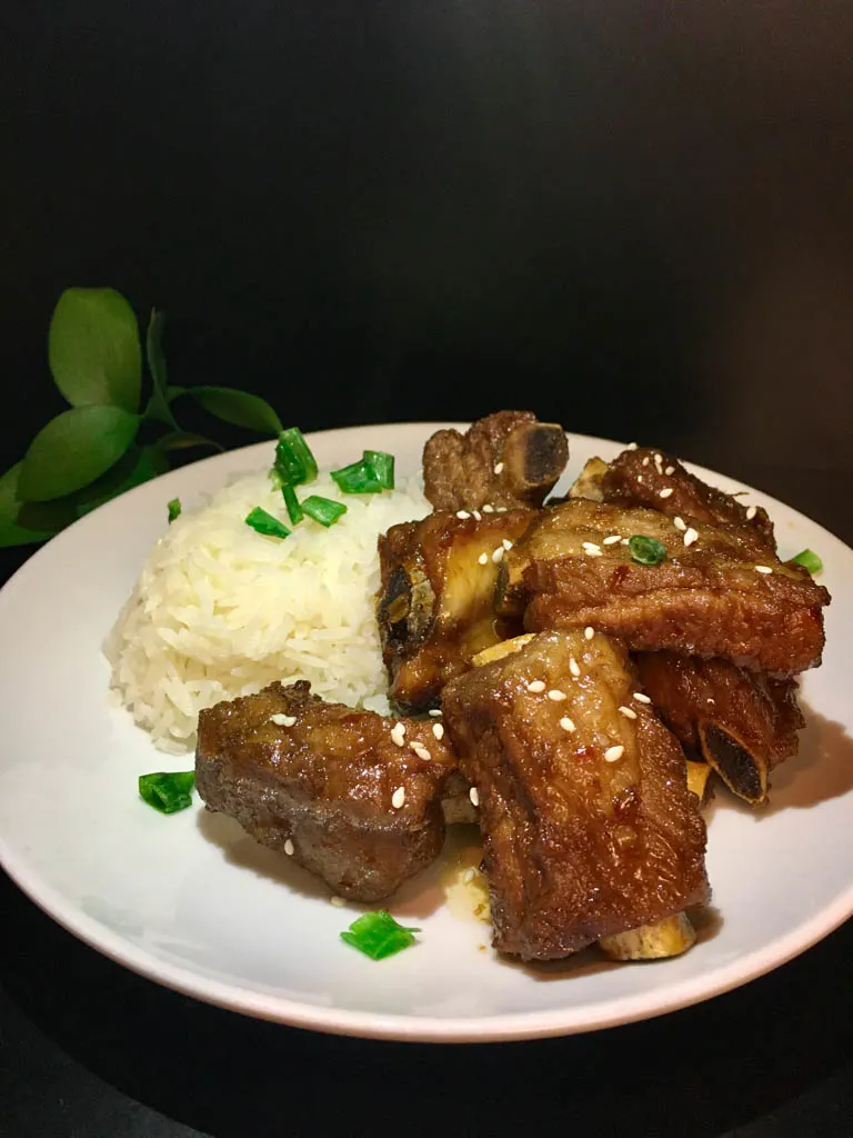 sticky short ribs plated with rice on a white plate