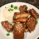 sticky short ribs plated with rice on a white plate