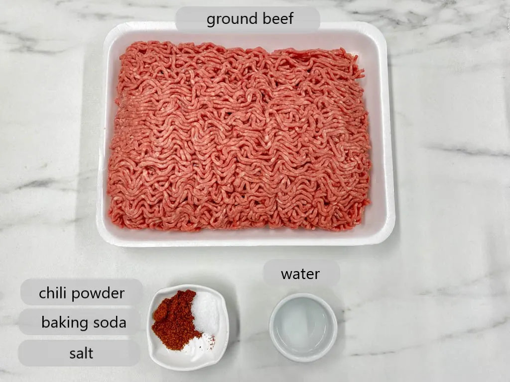 package of ground beef and bowl with water, chili powder, baking soda and salt