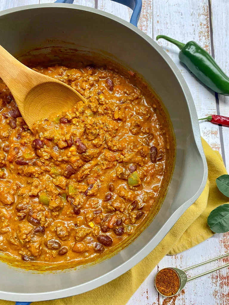 pot of chili with a wooden spoon and jalapeno on the side