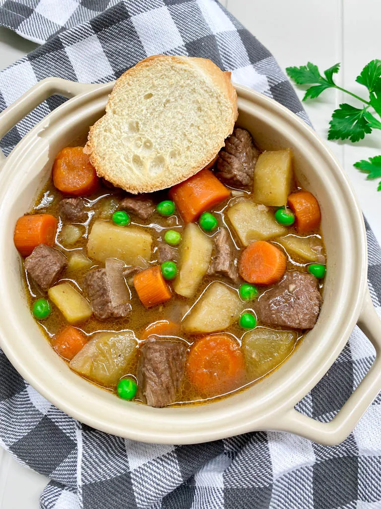 beef stew in a beige bowl with bread