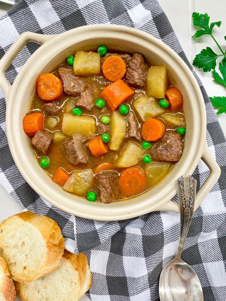 beef stew in a beige bowl with bread