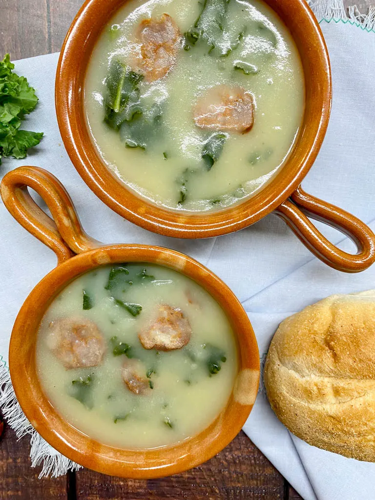 two bowls of caldo verde portuguese kale soup 2 brown bowls with bread