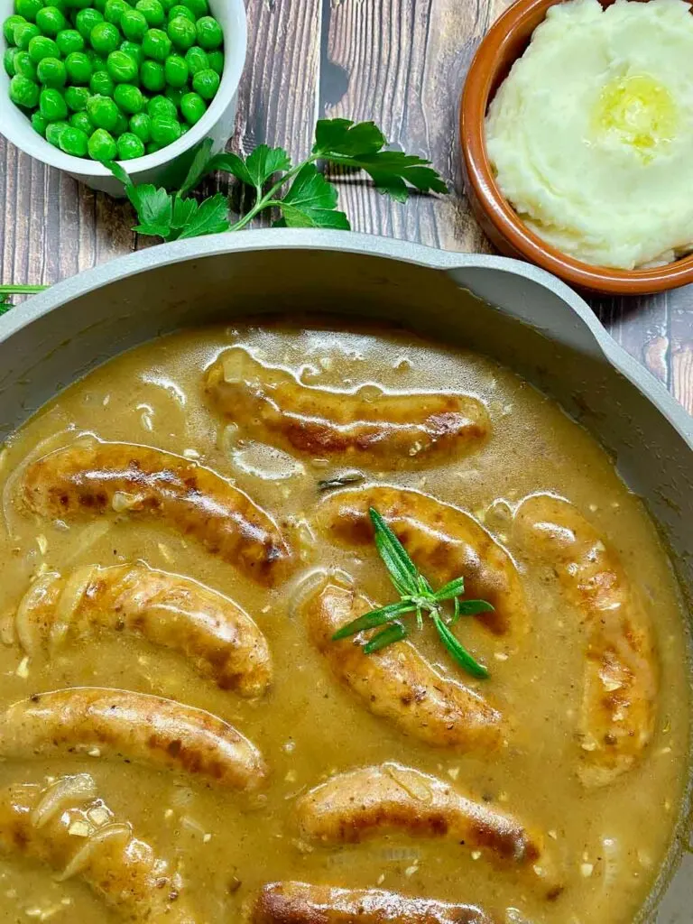 bangers and mash with peas, onion gravy and mashed potatoes