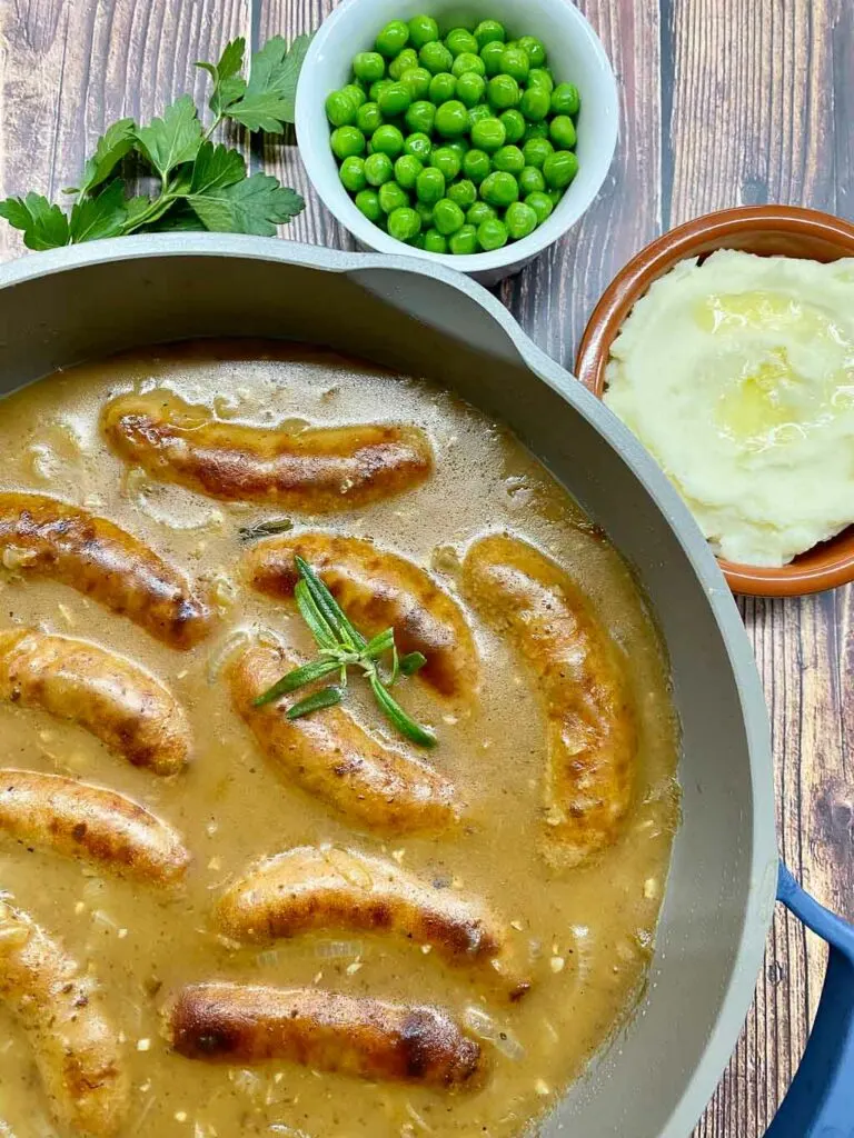 bangers and mash with peas, onion gravy and mashed potatoes