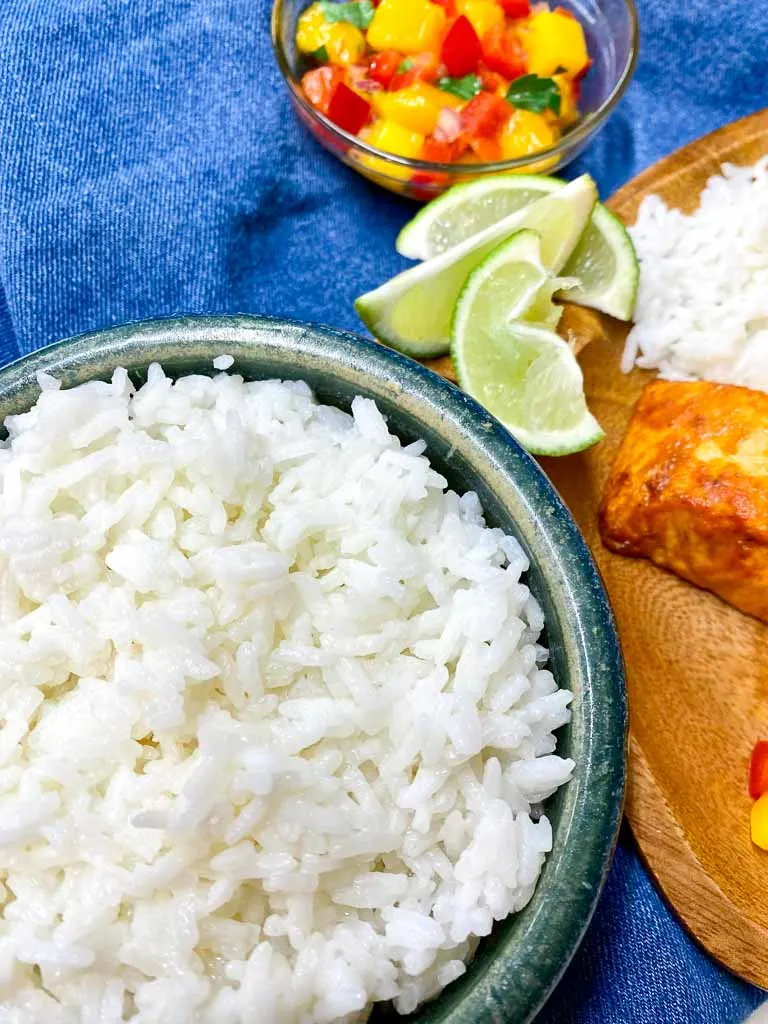 mango salsa salmon with coconut rice on a wood plate and a side of coconut rice and lime