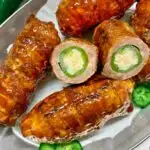 bacon wrapped armadillo eggs on a silver platter with parchment paper and sliced jalapenos