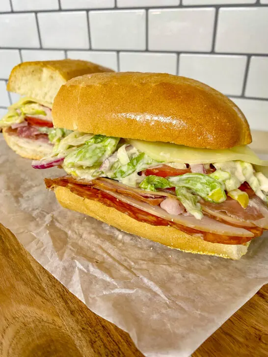 viral tikok italian grinder sandwich on parchment paper and a wood cutting board