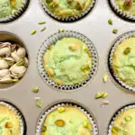 pistachio muffins in a muffin tin with crushed pistachios