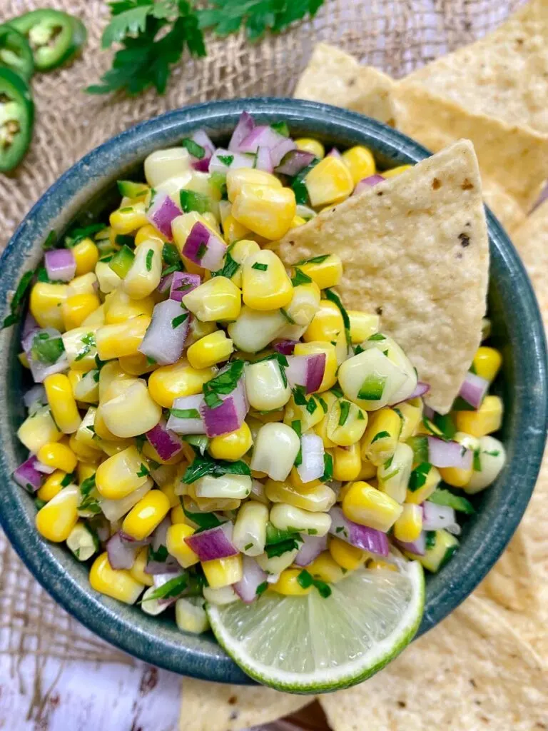 green bowl with Chipotle copycat corn salsa a lime wedge and tortilla chips