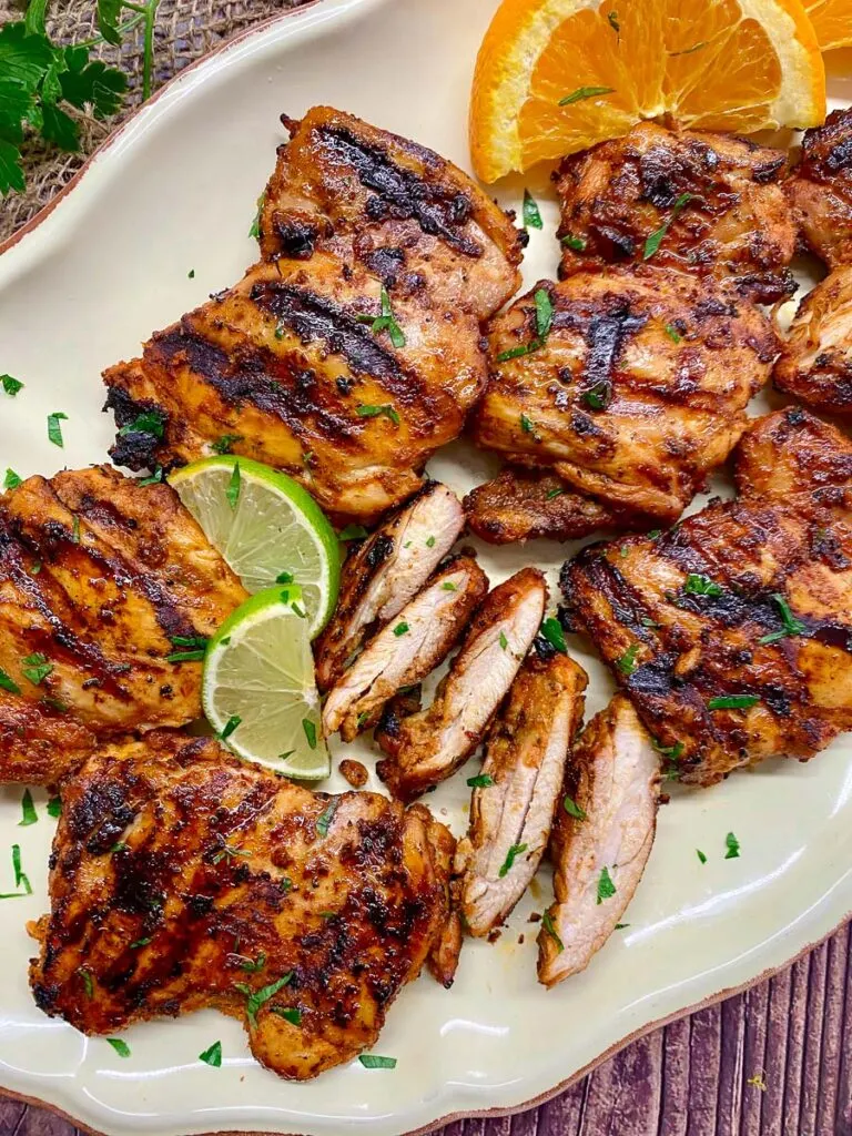 chipotle pollo asado copycat recipe on a white platter with lime and orange wedges