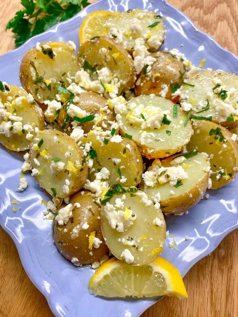 Greek feta potato salad on a blue plate with feta, lemon zest and parsley