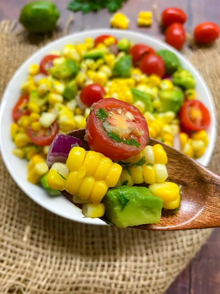 avocado corn tomato salad in a white bowl with burlap in the background