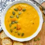 bowls of butternut squash soup garnished with pumpkin seeds, roasted squash and thyme