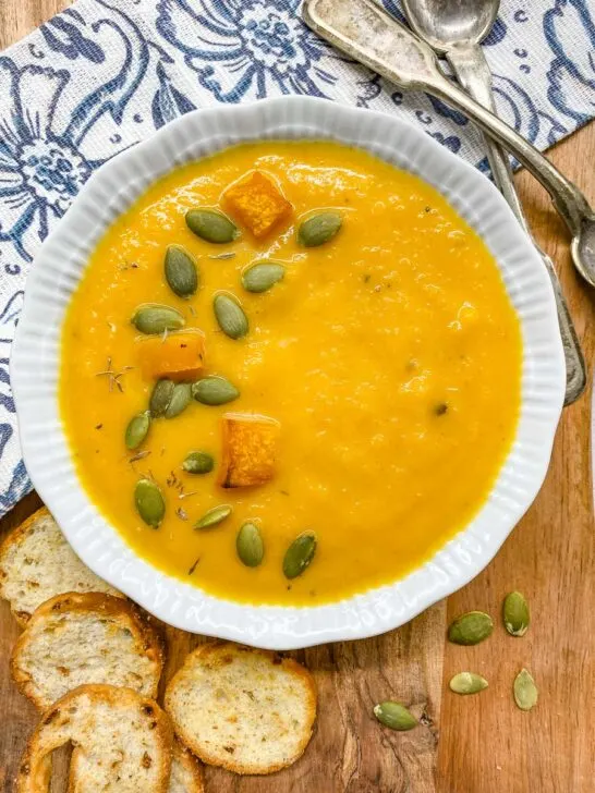 bowls of butternut squash soup garnished with pumpkin seeds, roasted squash and thyme