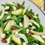 pear fennel arugula salad with goat cheese and pecans on a white platter