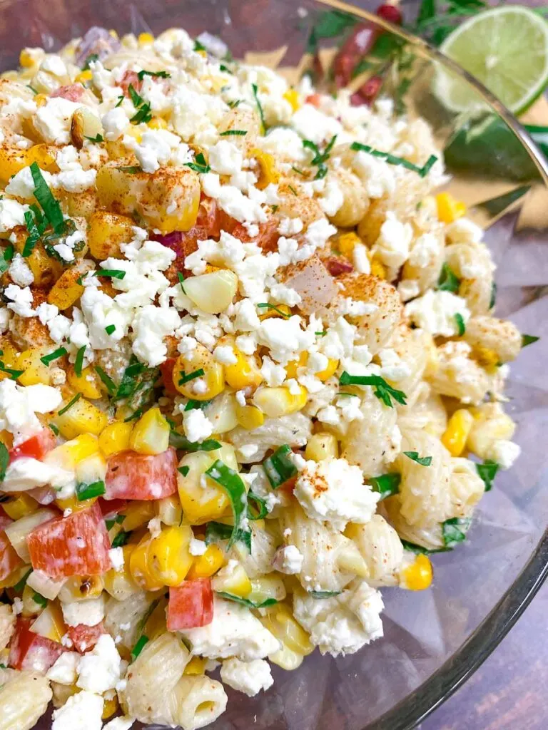 Mexican street corn pasta salad in a glass bowl garnished with jalapeno and cotija cheese