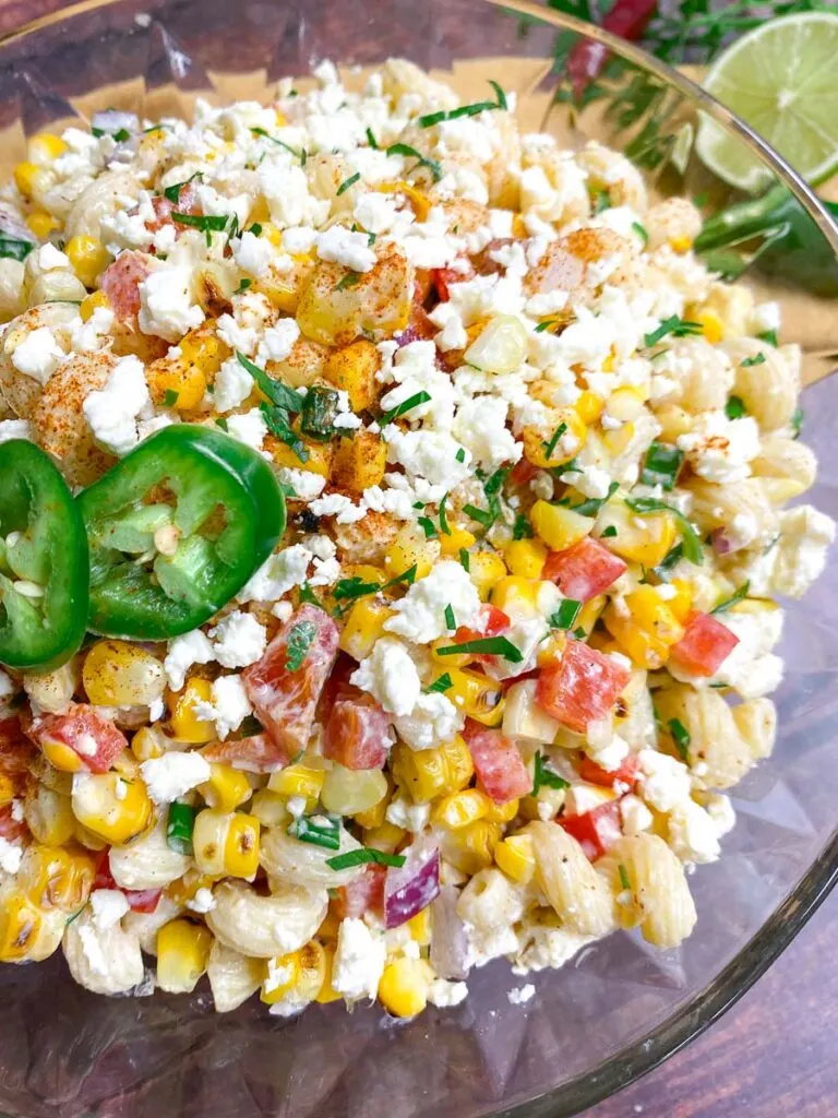 Mexican street corn pasta salad in a glass bowl garnished with jalapeno and cotija cheese