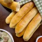 copycat olive garden breadsticks with a green checkerboard towel and marinara sauce to dip