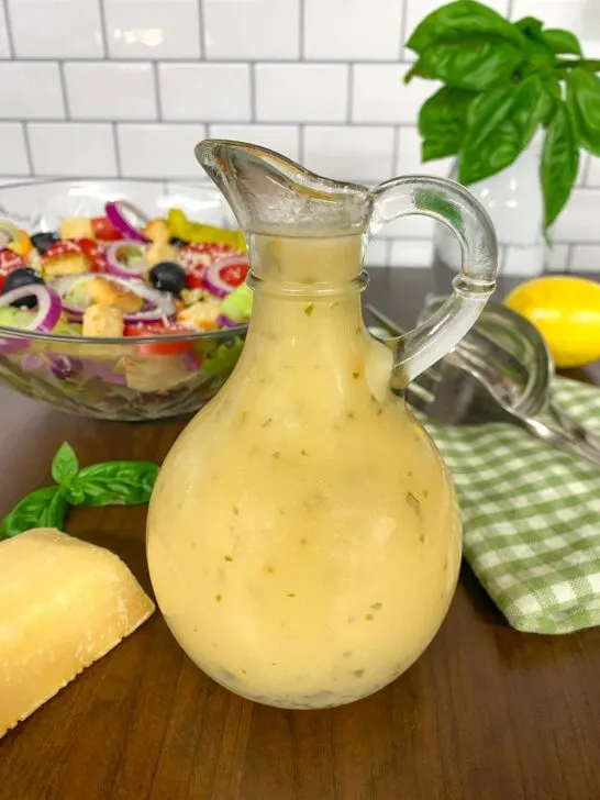 bottle of copycat olive garden salad dressing with salad in the background