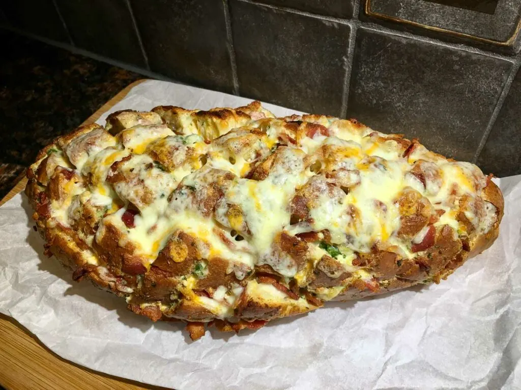 jalapeno popper pull apart garlic bread in a wood board with parchment paper