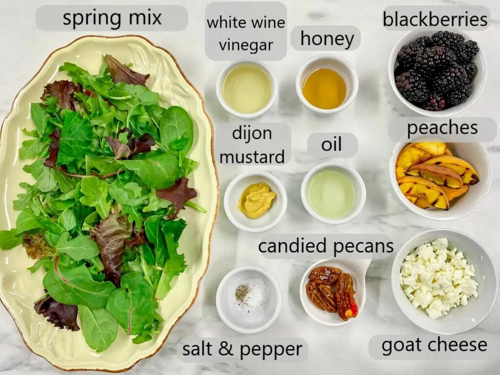 bowls with spring mix, black berries, peaches, goat cheese, candied pecans, white wine vinegar, honey, Dijon mustard, oil, salt and pepper to make salad.