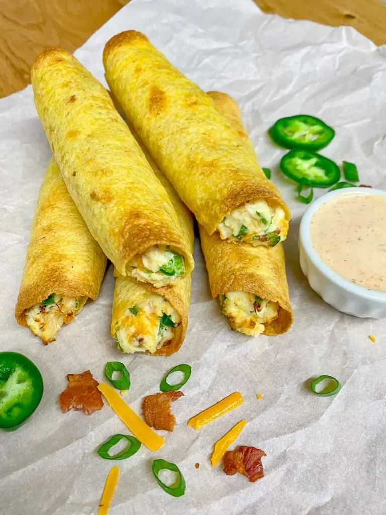 jalapeno popper chicken taquitos on parchment paper