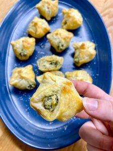 spinach artichoke dip bites on a blue plate with parmesan cheese