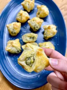 spinach artichoke dip bites on a blue plate with parmesan cheese