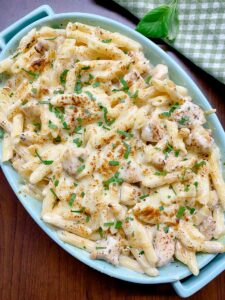 chicken alfredo bake in a blue baking dish garnished with parsley